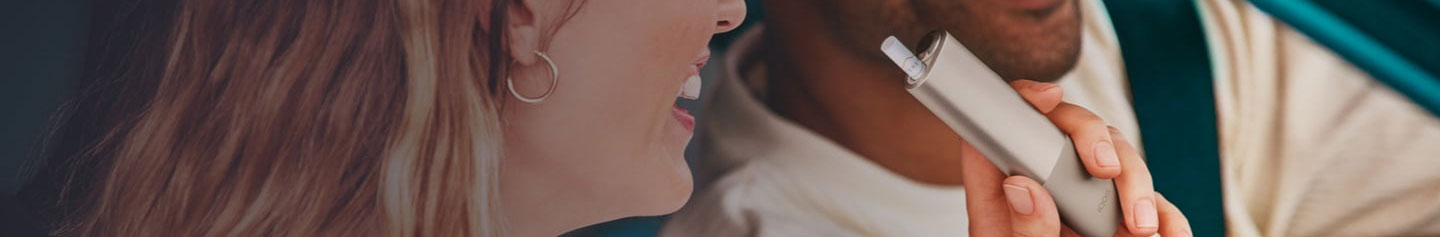 An IQOS device held by one person and a smartphone held by another person.